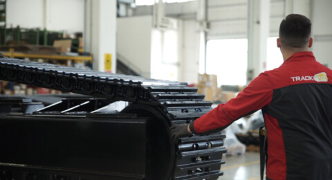 Pracovník kontrolující systém podvozku pásového vozidla v výrobnej hale.