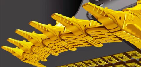 Žlté kovové zuby stavebného stroja v detailnom zábere.